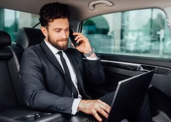 handsome-bearded-smiling-businessman-working-his-laptopand-speaking-mobile-phone-backseat-car_496169-578